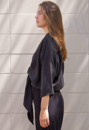Side view of straight size model wearing Black Lyocell Bow Top.