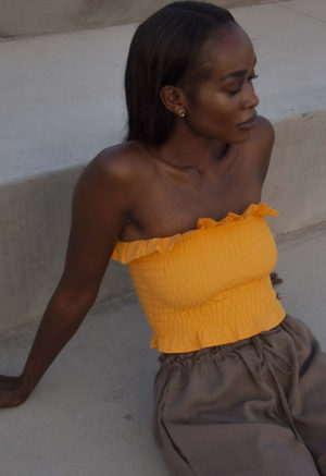 Front/side view of straight size model wearing Gold Ruffle Tube Top.