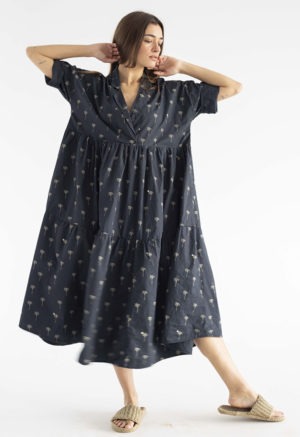 woman in black cotton tiered lapel dress with palm tree pattern.