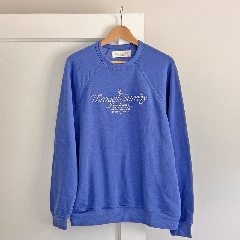 blue sweatshirt with white embroidered writing at chest