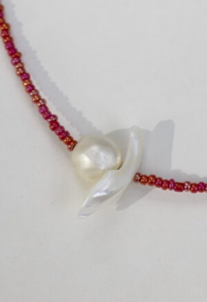 red necklace with pearl center on white backdrop