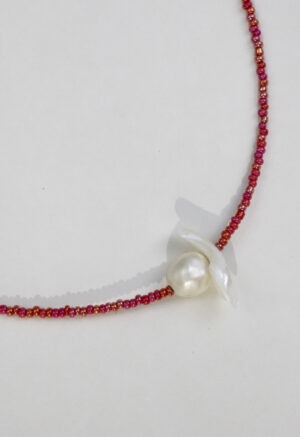 red necklace with pearl center on white backdrop