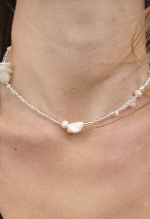 woman in black v-neck and clear and white beaded necklace