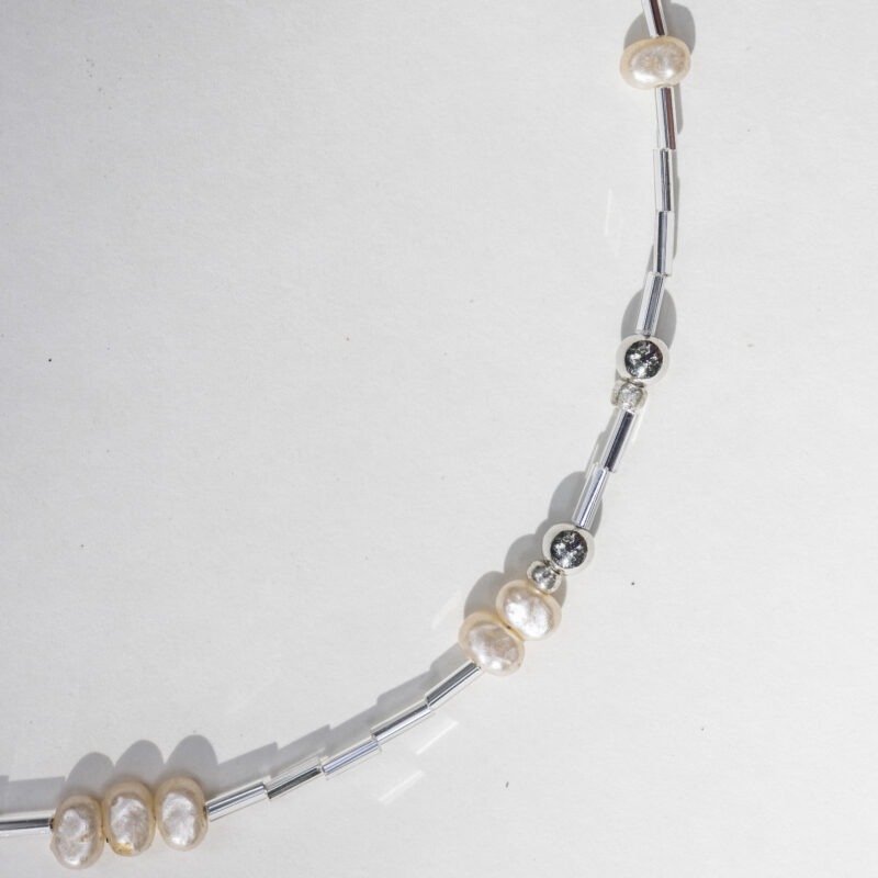 pearl and silver necklace on white backdrop