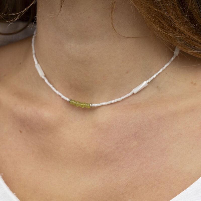 woman in white top and white and green necklace