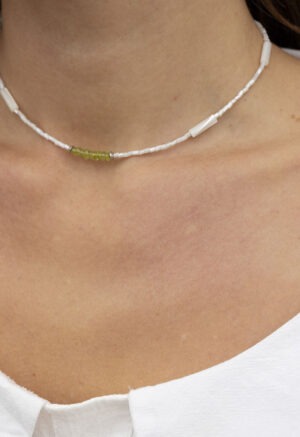 woman in white top and white and green necklace