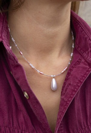 woman in maroon button-up and pink pearl necklace