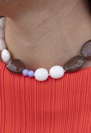 woman in red top and large beaded white, brown and blue necklace