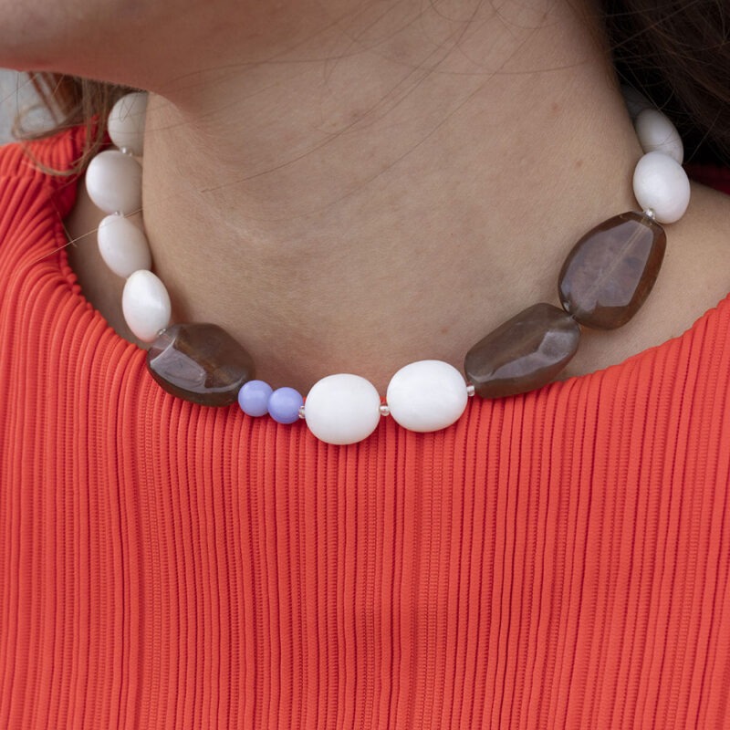 woman in red top and large beaded white, brown and blue necklace