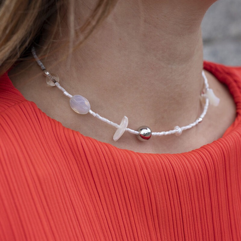 woman in red top with white silver and pearl necklace