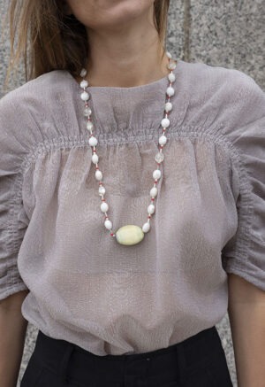 woman in grey shirt and extra long white, red and rock necklace