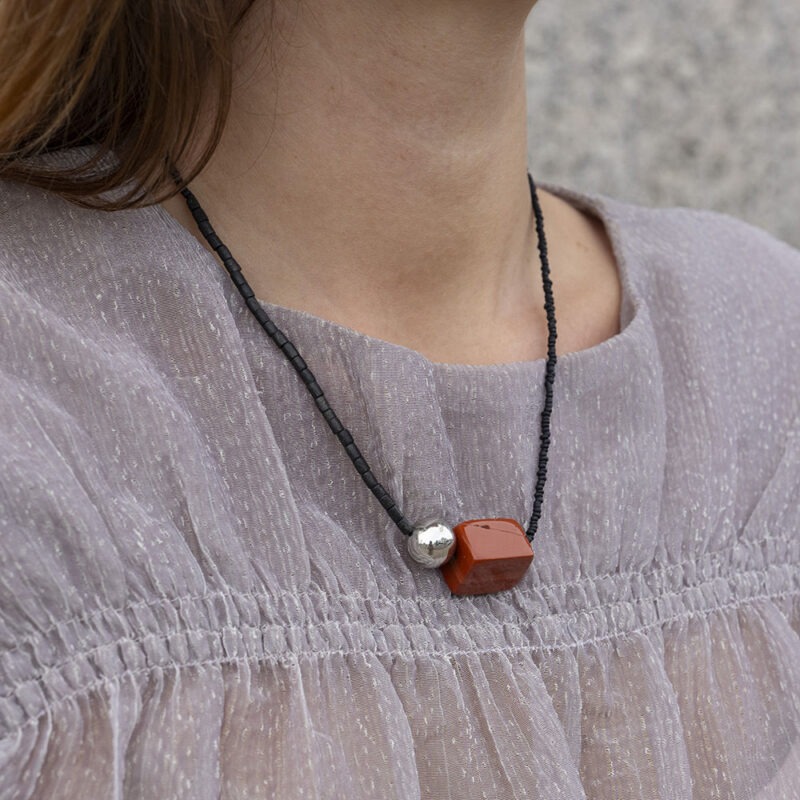woman in grey top with black and red stone necklace