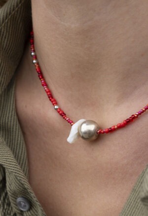 woman in green button-up with red silver and pearl necklace