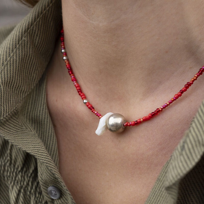 woman in green button-up with red silver and pearl necklace