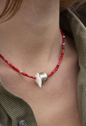woman in green button-up with red silver and pearl necklace