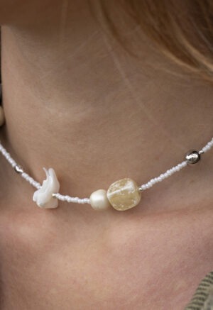 woman in green button-up with white beaded shell and stone necklace