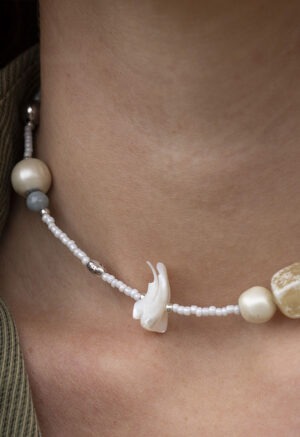 woman in green button-up with white beaded shell and stone necklace