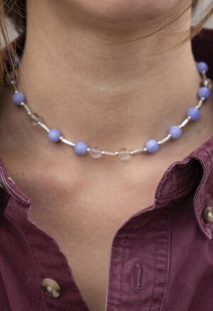 woman in maroon button-up and blue and white beaded necklace