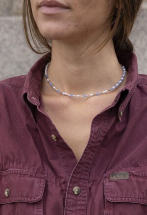 woman in maroon button-up and light blue and pearl necklace