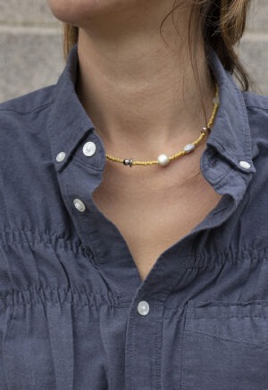 woman in dark grey button-up with yellow beaded necklace