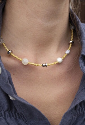 woman in dark grey button-up with yellow beaded necklace