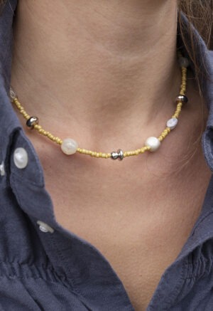 woman in dark grey button-up with yellow beaded necklace