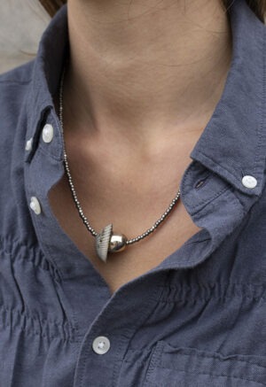 woman in grey button-up with grey and silver shell necklace