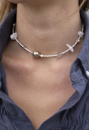 woman in grey shirt in White and silver necklace of various jems