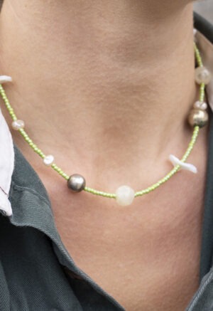 woman in green button-up with light green shell necklace