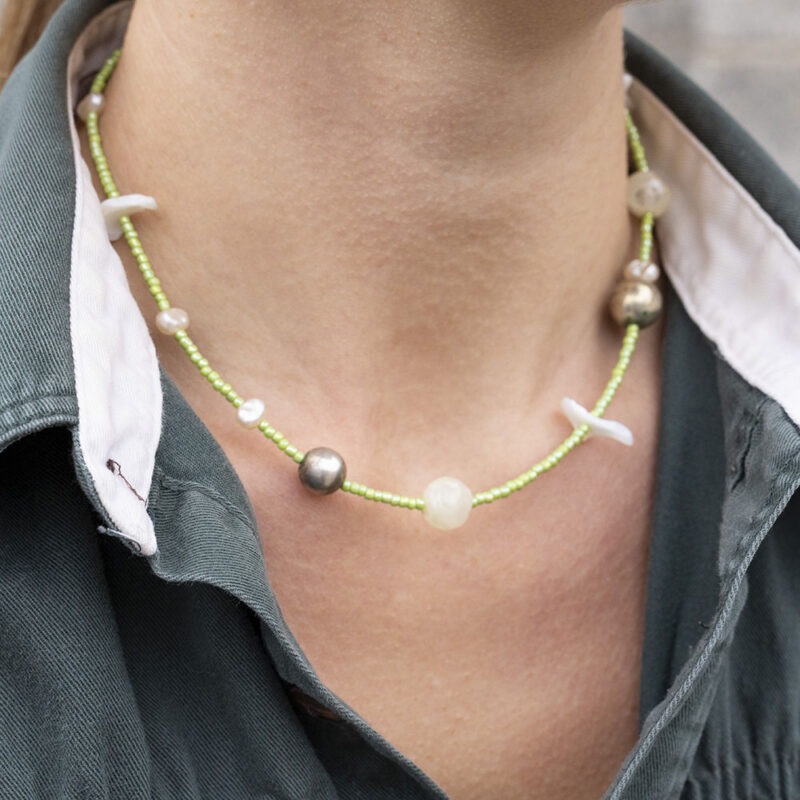 woman in green button-up with light green shell necklace