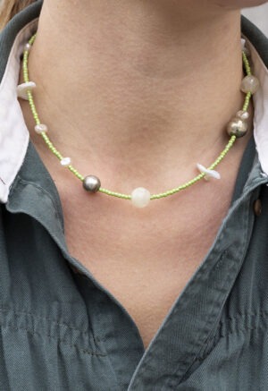 woman in green button-up with light green shell necklace
