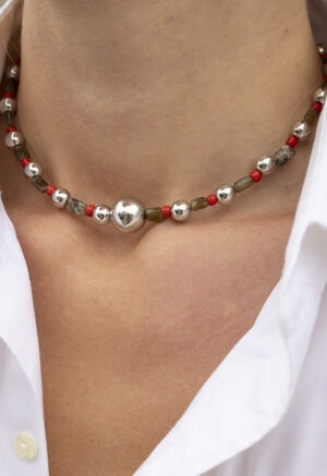 woman in white button-up with red, green and silver necklace