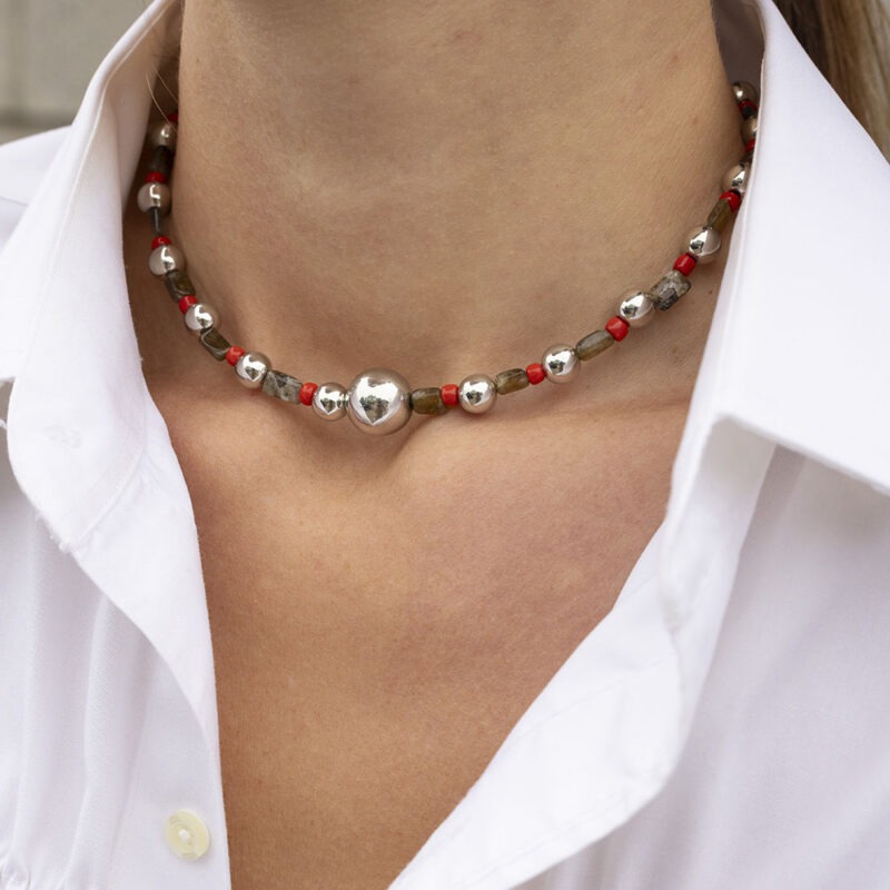 woman in white button-up with red, green and silver necklace