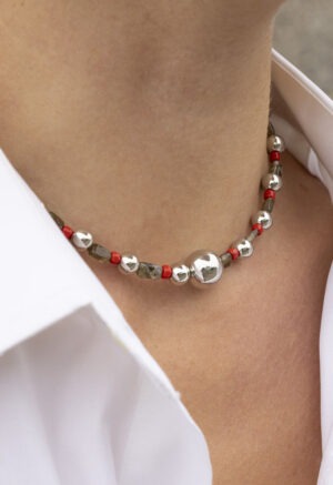 woman in white button-up with red, green and silver necklace