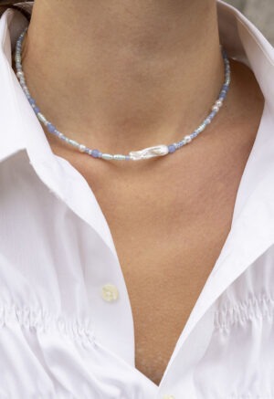 woman in white button-up and blue pearl necklace