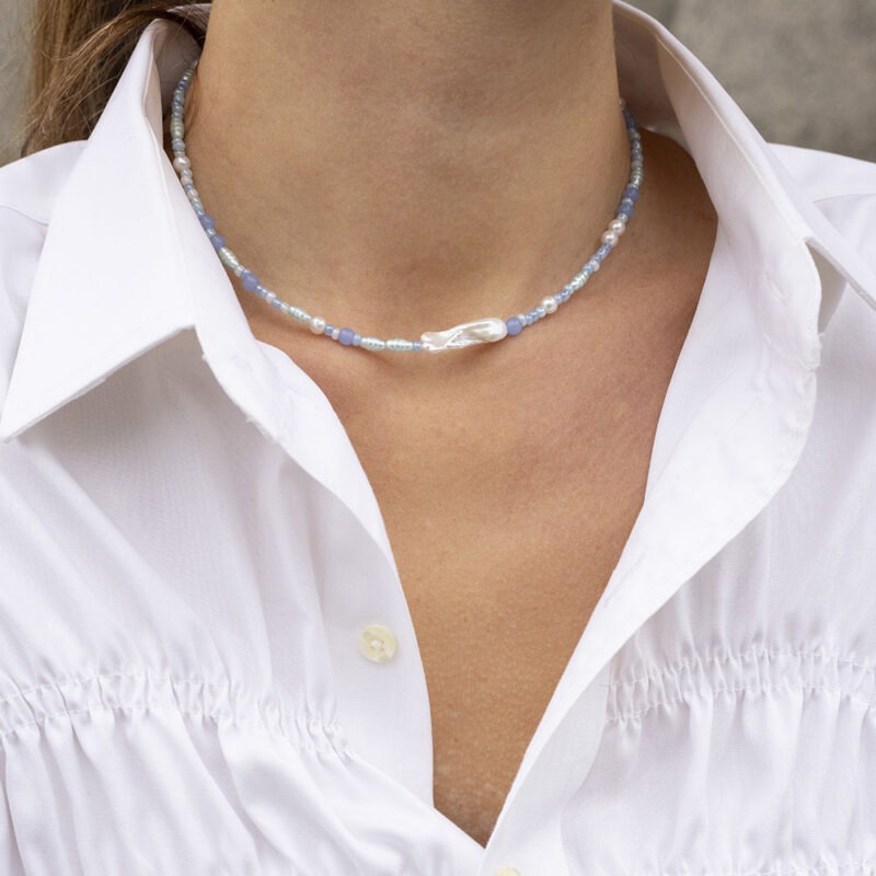 woman in white button-up and blue pearl necklace