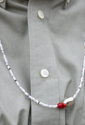 woman in grey button-up with white and grey necklace with silver stone