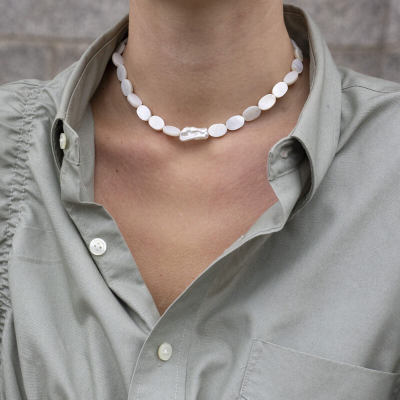 woman in grey shirt and pearl necklace
