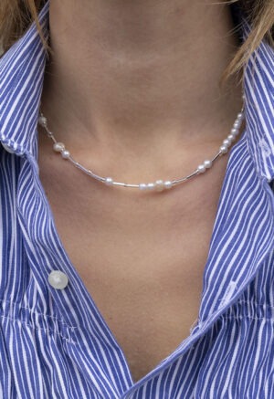 woman in blue and white strip button-up with glass and pearl beaded necklace