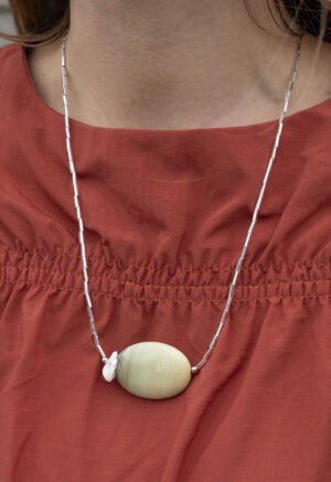 woman in burnt orange top and long silver and rock necklace.