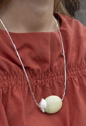 woman in burnt orange top and long silver and rock necklace.