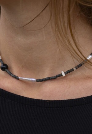 Woman wearing black necklace with black and pearl beads