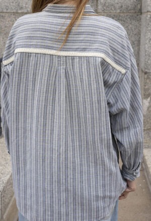 woman in blue and white stripe button-up and jeans