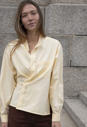 woman in pale yellow button-up wrap top and brown pants